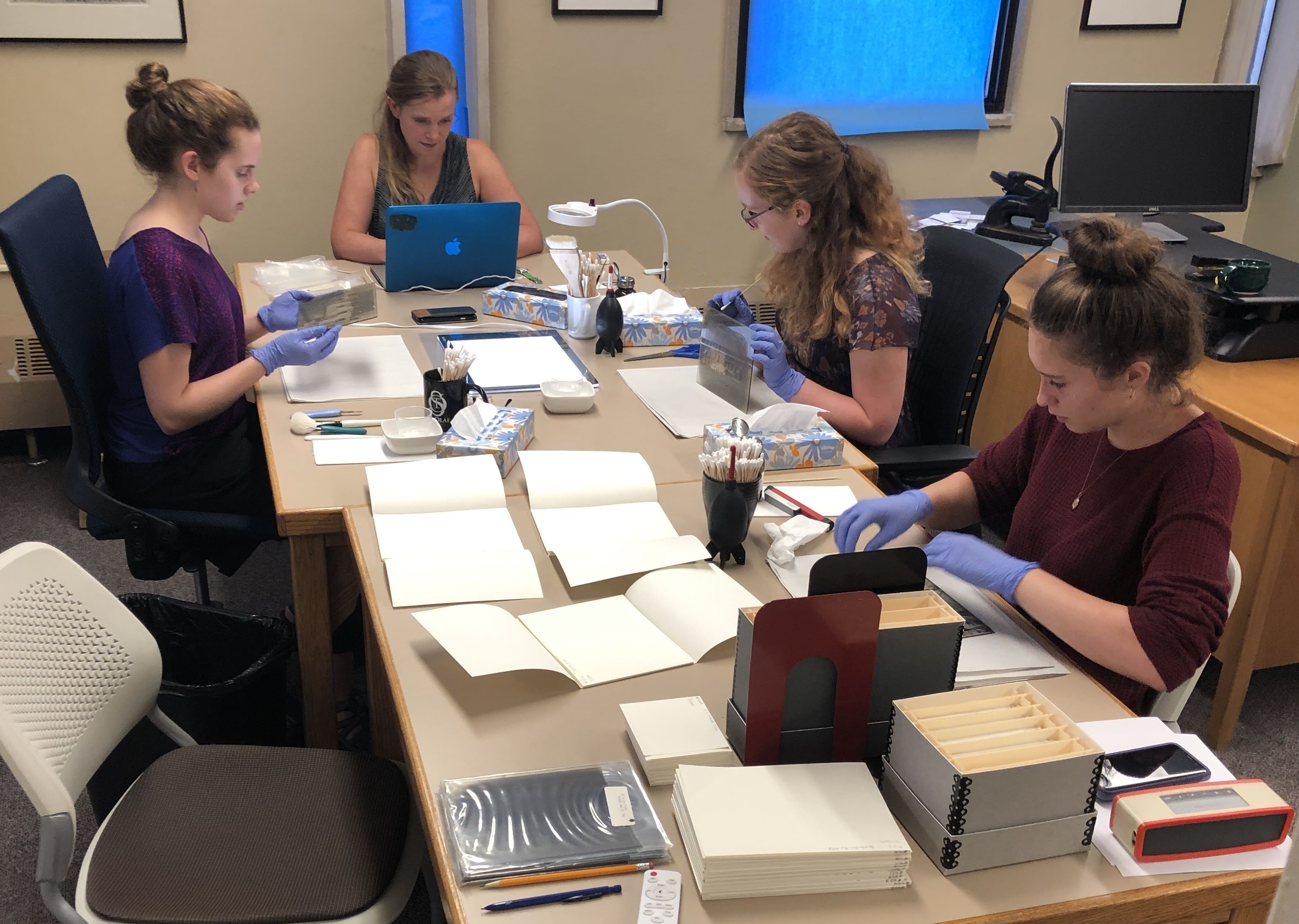 CCAHA staff and St. Olaf College library staff working together on glas plate negative treatment during a 2018 site visit. 