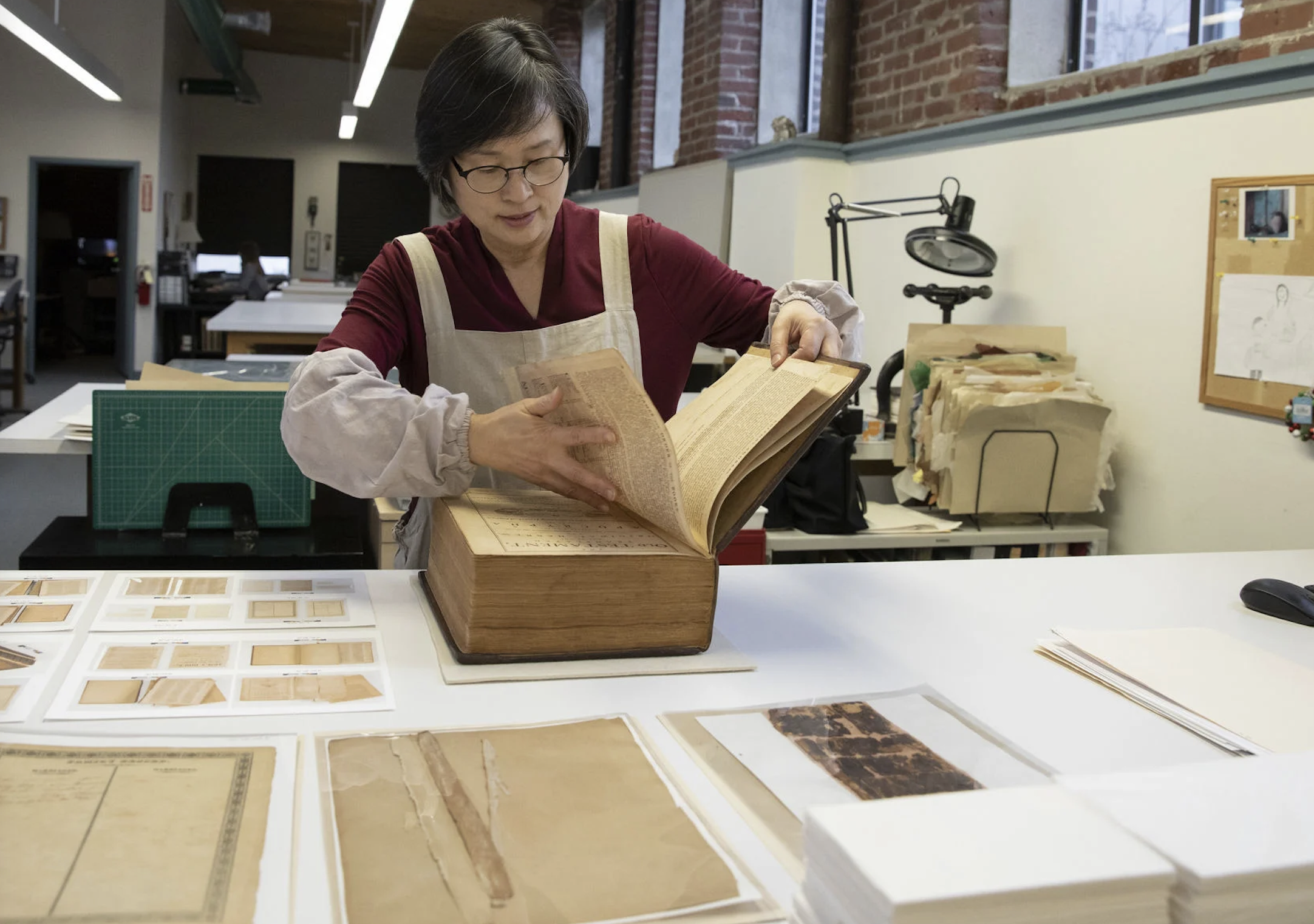 Senior Book Conservator Jungohk Theresa Cho turns a page of the 1,300-page Betsy Ross family Bible in the CCAHA book lab during its 50-hour stabilization treatment, which restored the volume’s crumbling spine and handwritten family registry of births, marriages, and deaths.