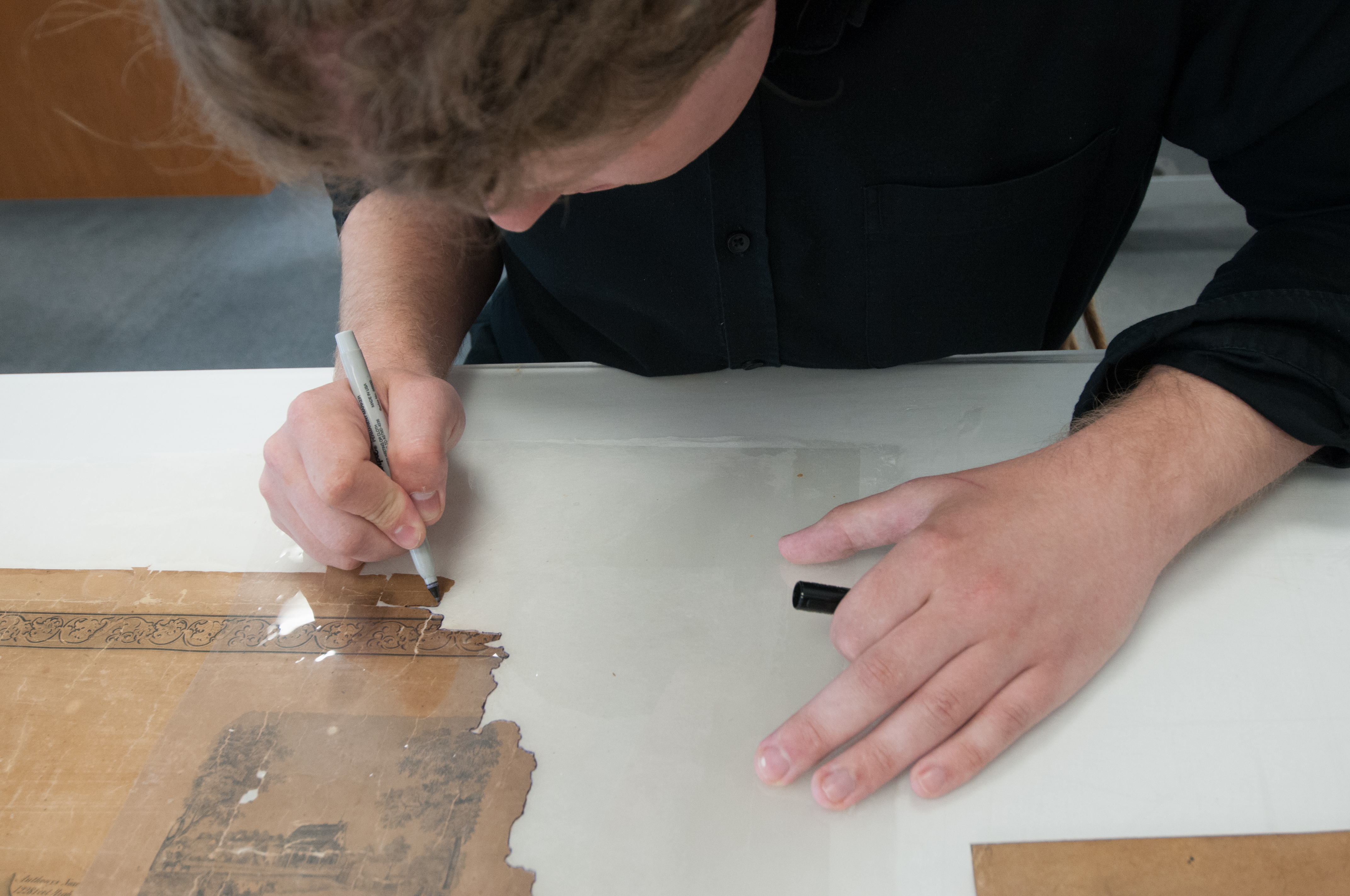 Paper Conservation Fellow Benjamin Kirschner treating a map's corner