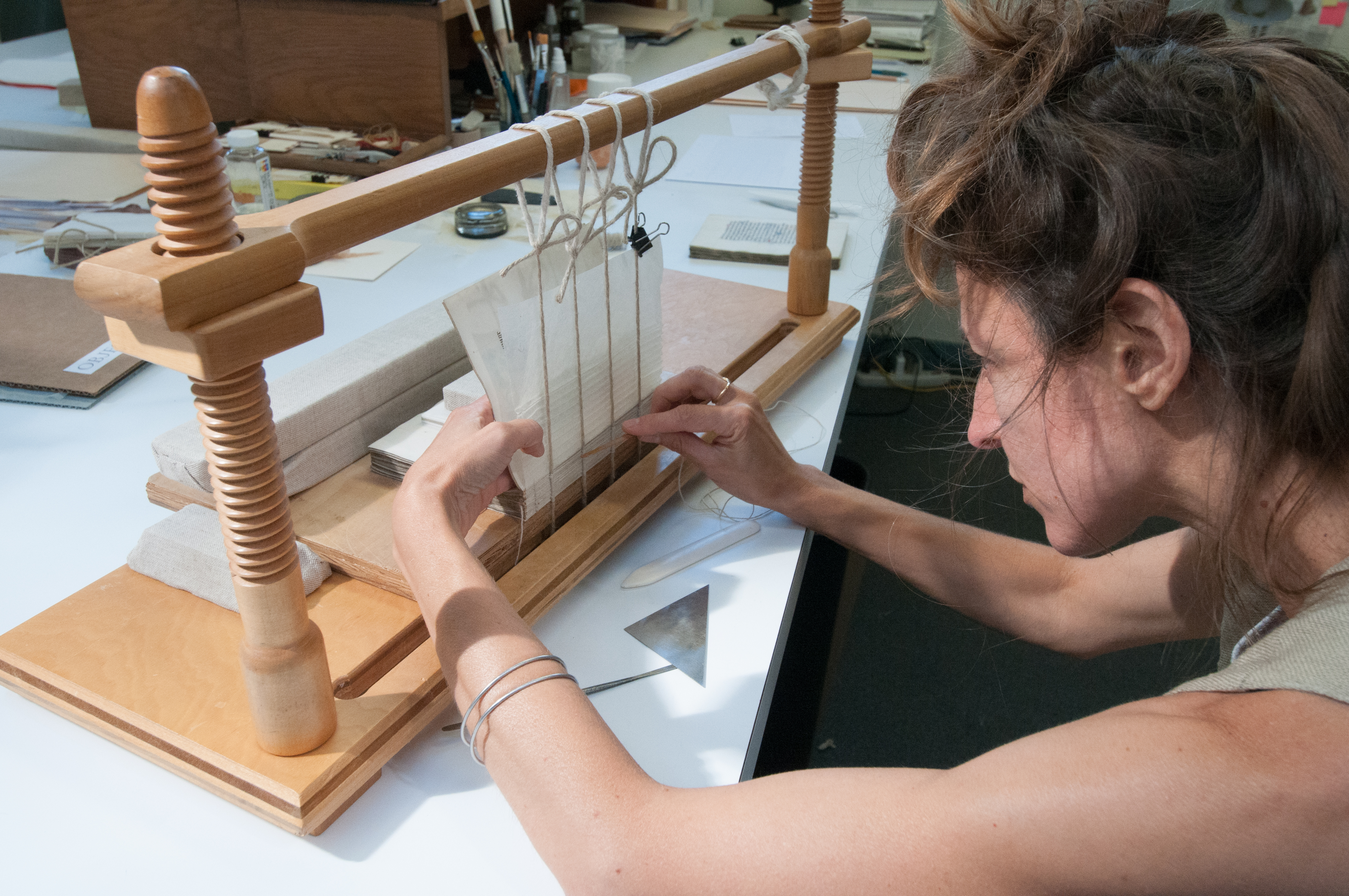 Book Conservator Amber Hares resews the bookblock using a mulberry paper concertina