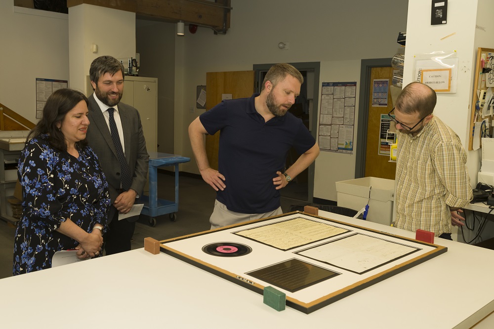 CCAHA Executive Director Michelle Eisenberg, Manager of Marketing & External Relations Jason Henn, Representative Ben Waxman, and Manager of Housing & Framing Joshua Rickards get an up-close look at a beloved Philadelphia artifact, the original sheet music for the 6abc Action News theme song.