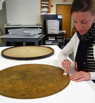 Conservator cleaning the map with a soft sponge