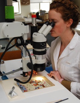 Marianne de Bovis looks through microscope while consolidating media on Persian miniature