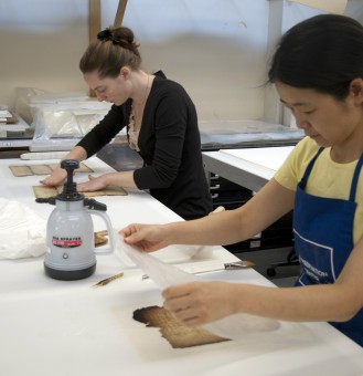 Two conservators treat fire-damaged documents