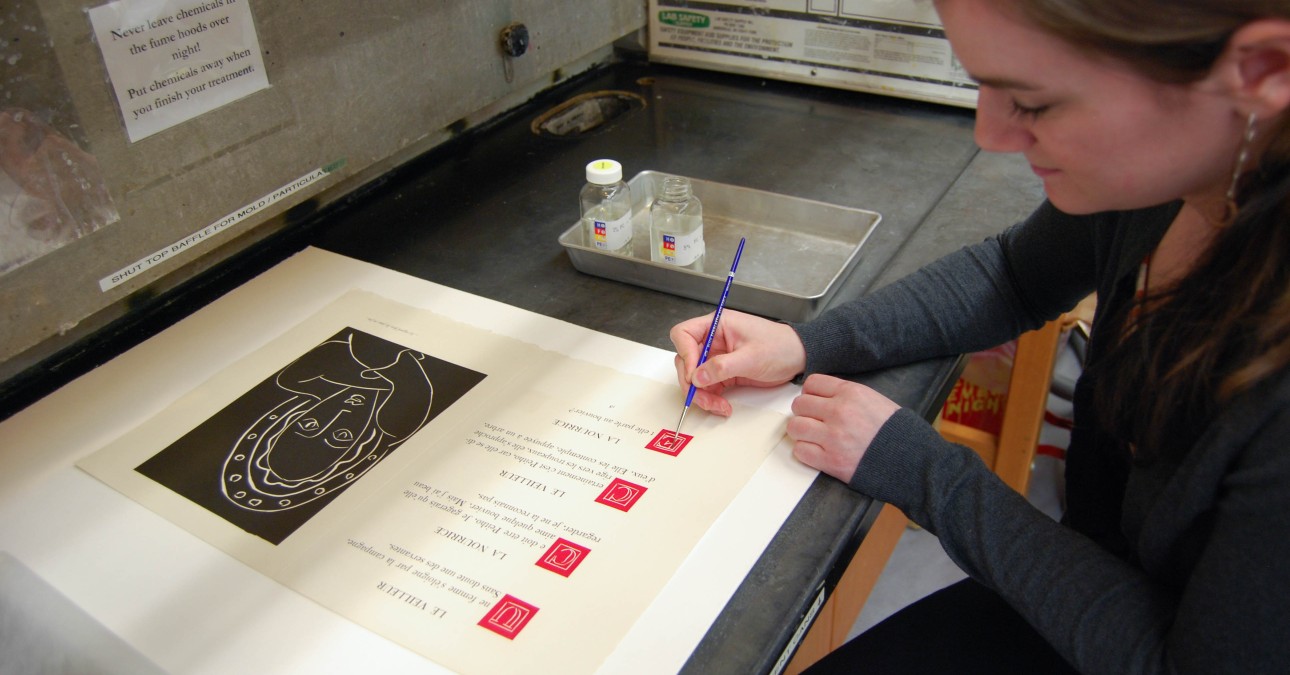 Conservator applies fixative to an area of red ink on a folio