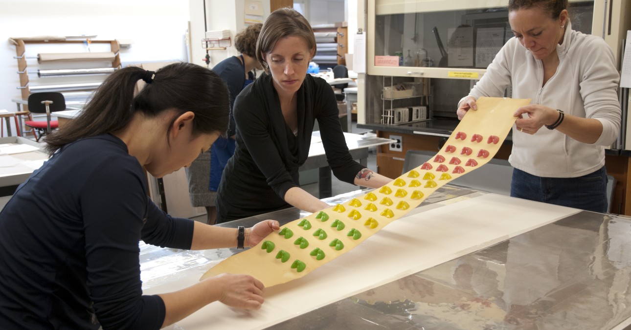 Conservators transfer the candy bottoms piece to a suction table