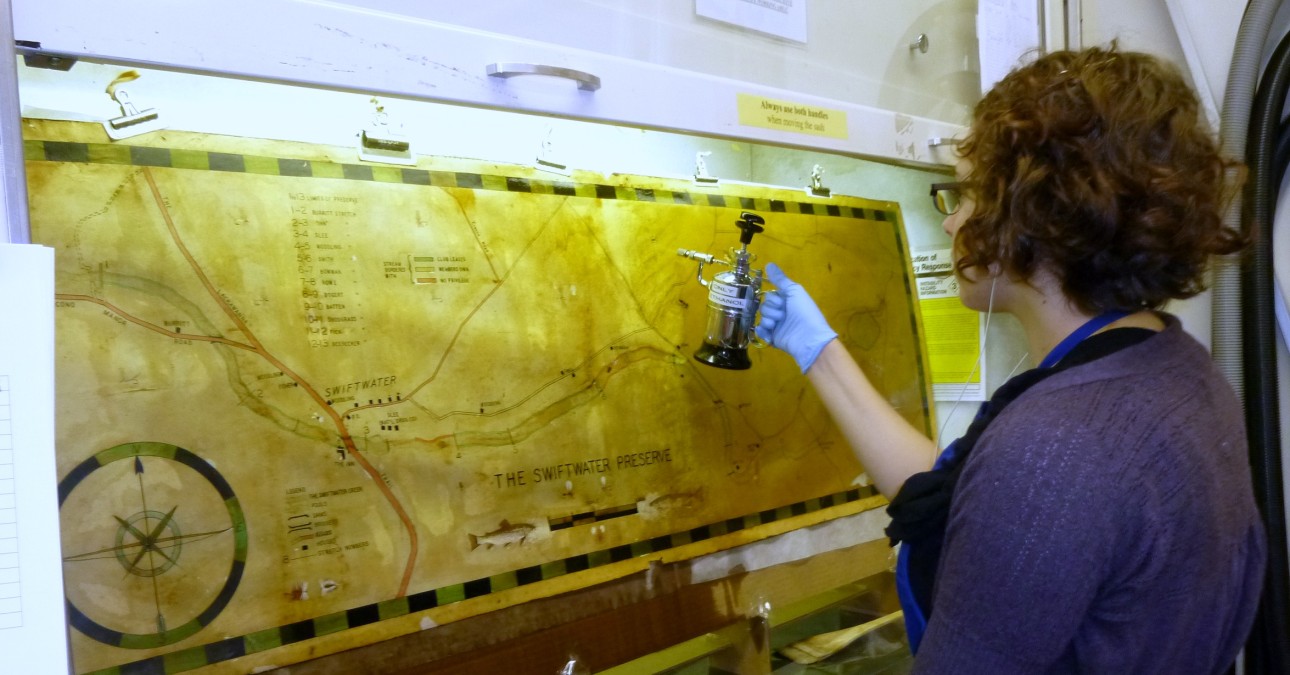 Conservator sprays solvent on map