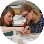 Two women intently look at an artifact