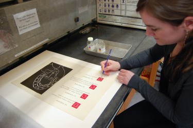 Conservator applies fixative to an area of red ink on a folio