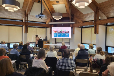 A presenter speaks to a large audience.